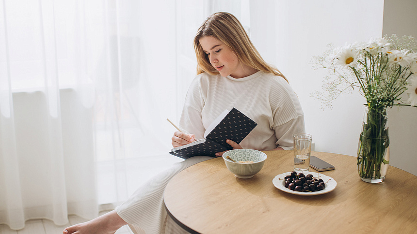 девушка пишет в блокноте за столом